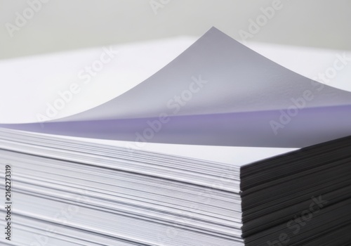 Stack of white paper sheets with one corner folded up isolated on white background