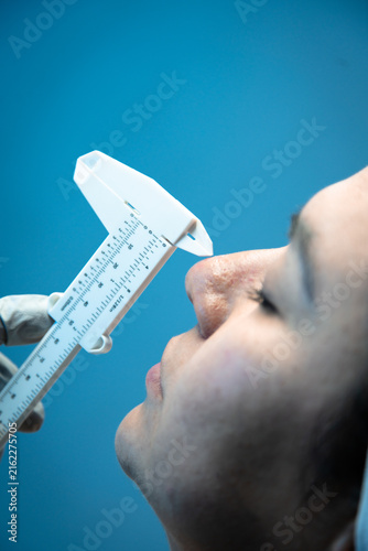 Fotografie Close-up of doctor measuring woman's nose with facial caliper