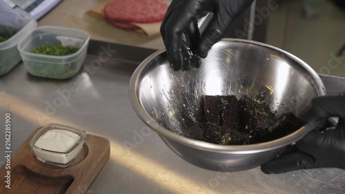 A close-up of a chef preparing deep-fried brown bread crackers with garlic in the restaurant kitchen on a wooden plate. Fast food. The cook is preparing snacks for beer.