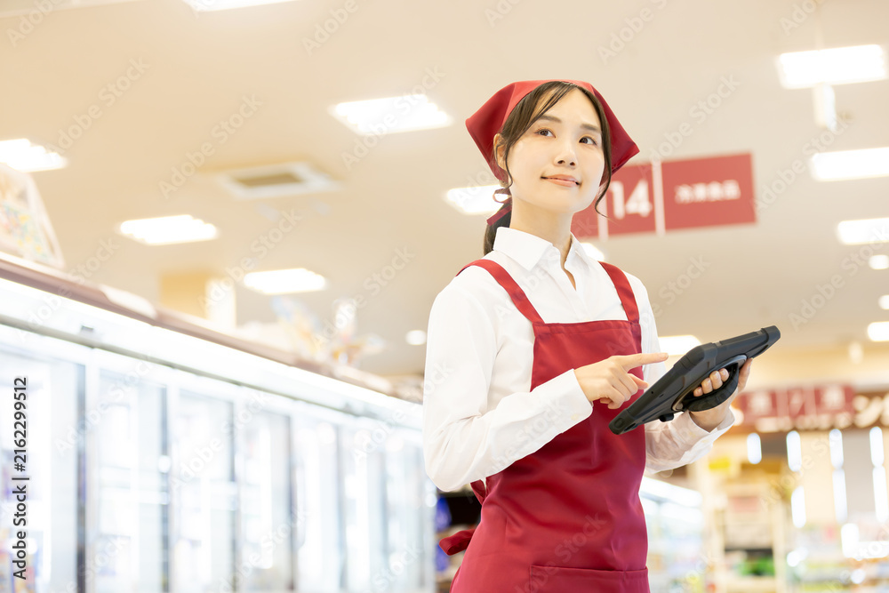 Fototapeta premium スーパーの冷蔵売り場でタブレットを使い商品管理をする女性店員