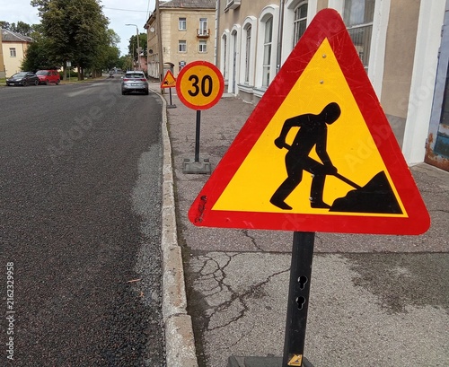 Urban Roadway Construction Worker Warning and 30 km/h Speed Limit Signs on European Street.

