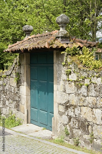 Old stone wall with green door and tiled roof. Portugal - Norte