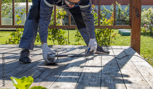 Fotografie Carpenter fastening wood on deck with hammer