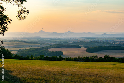 фотографія Hot air balloon floating over hazy hills of Ceske Stredohori mountain range near