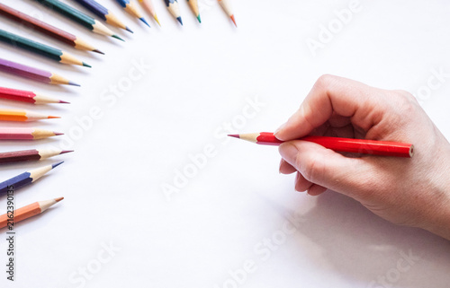 Hand using colored pencils to draw pink heart on white paper, close up. Hand, colored pencils, draw, heart, pink, paper, close up
