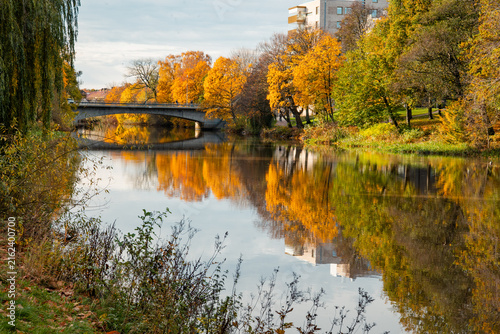 Calm river surrounded by colorful autumn trees in Skåne, Sweden. Peaceful seasonal landscape, creating a scenic atmosphere for outdoor recreation and travel.