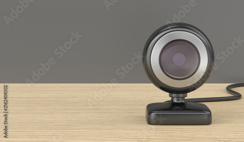 Front view of black webcam on wooden desk, copy space