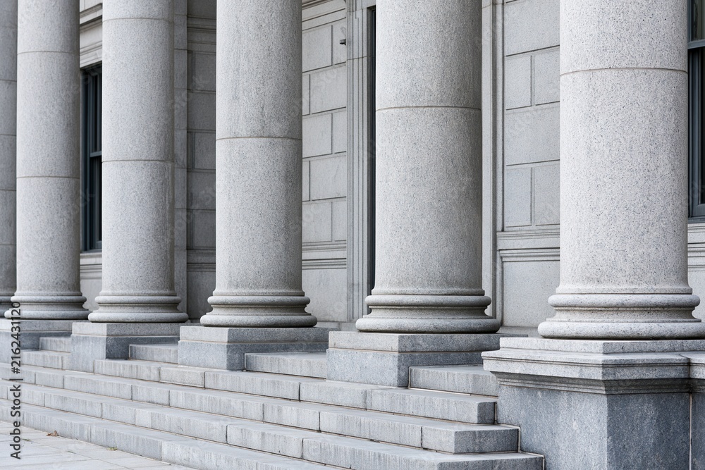 Fototapeta premium Row of Imposing Classical Stone Pillars and Steps Leading to an Ornate Building Facade