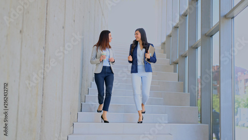 Konstfotografi Business women walking downstairs talking in office building