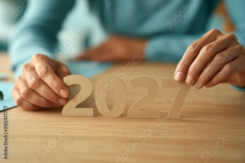 Hands arranging New Year numbers on a wooden desk, holiday planning, creative workspace, festive greeting, Christmas, New Year.