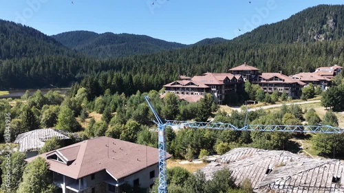 Aerial view showing contrast between an abandoned construction site and modern mountain resort hotels