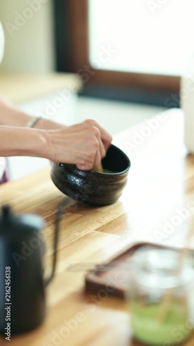 Hands Whisking Matcha in Traditional Black Ceramic Bowl on Wooden Table Japanese Tea Ceremony