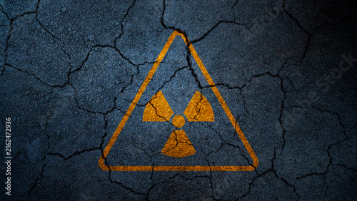 Konstfotografi Yellow radioactive hazard symbol painted on a dark, cracked asphalt texture, symbolizing nuclear danger and post-apocalyptic ruin
