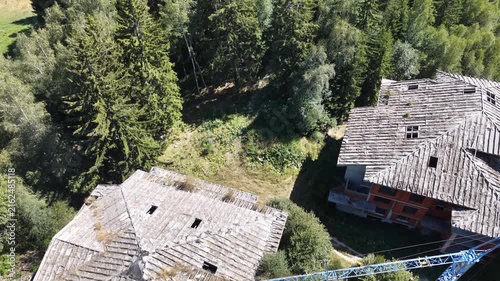 Top-down aerial view of an abandoned building construction site with a blue crane and 5G cell tower