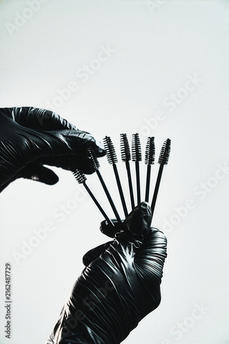 Gloved hand holding a fan of black mascara wands