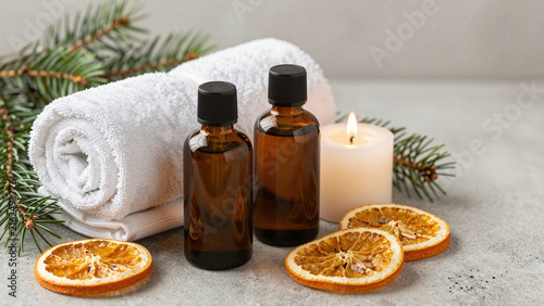 Christmas aromatherapy still life with amber bottles, towels, candle and dried oranges