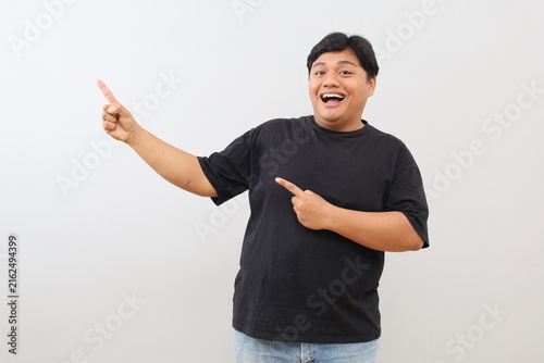 Foto A photo of a heavy-set man looking both surprised and happy, pointing his index finger to the side into empty space against a white background