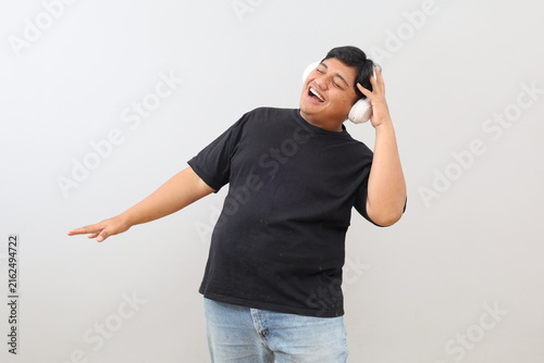 Foto A cheerful and laid-back heavy-set man listening to music through headphones, dancing, singing, and having fun against a white background