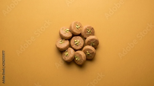 Peda sweets are arranged on a yellow background.