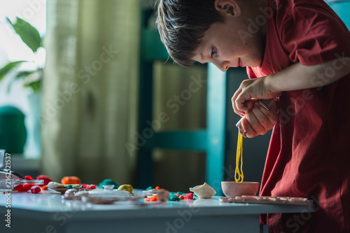 Boy plays with play dough at home developing creativity