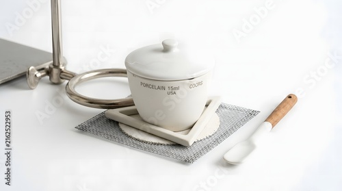 Porcelain crucible with lid sits on ceramic triangle and wire gauze for chemical analysis.