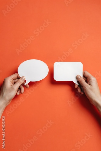 Hands holding white speech bubbles on orange background