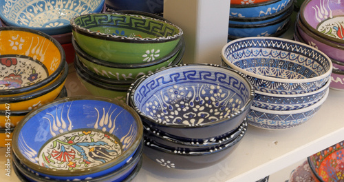 View of colorful hand-painted ceramic bowls with traditional Greek patterns displayed on a shelf in Mykonos, Greece.