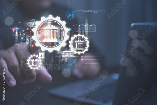 A person uses a laptop to manage digital banking systems with the help of artificial intelligence. Futuristic gears and bank icons glow on a screen to show smart financial technology.