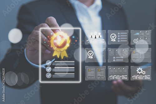 A businessman holds a digital pen to select a glowing quality assurance certificate with digital compliance checklists and certification documents.