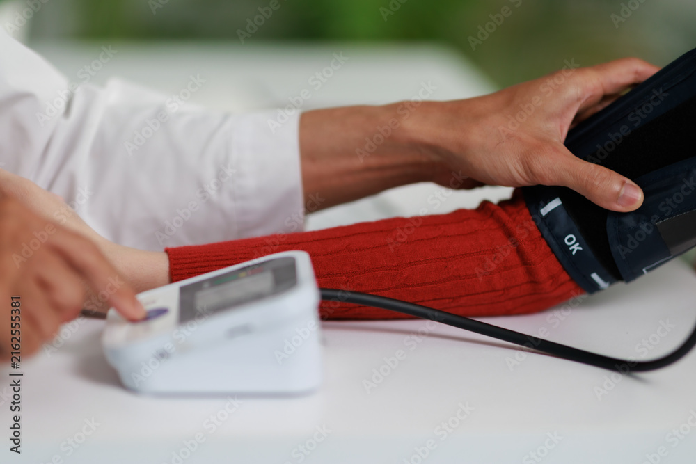 Fototapeta premium Healthcare professional monitoring patient's blood pressure using a digital sphygmomanometer during a medical checkup, focusing on prevention and early detection of hypertension