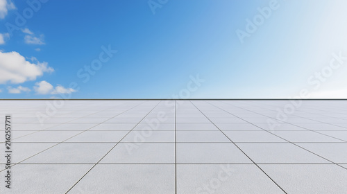 A large area of white square tiled ground extends to the horizon beneath a deep blue sky with scattered white clouds.