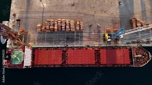 Ship occupies harbor.
Port surrounds vessel.
Drone captures cargo.
Crane serves terminal.