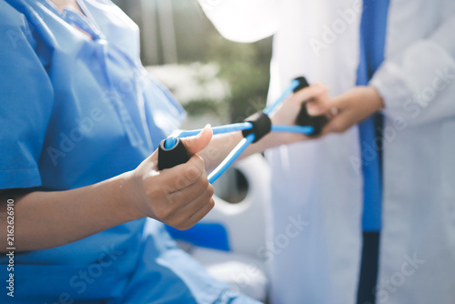 Physical therapist giving stretching exercises with elastic exercise bands and physical therapist hands helping male patient Physical therapy concept