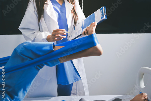 Doctor checks Asian senior woman patient after knee replacement operation in hospital room. Nurse examines leg after surgery. Medicine health treatment therapy healthcare concept