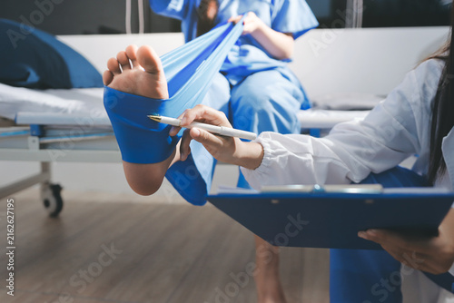 Doctor checks Asian senior woman patient after knee replacement operation in hospital room. Nurse examines leg after surgery. Medicine health treatment therapy healthcare concept