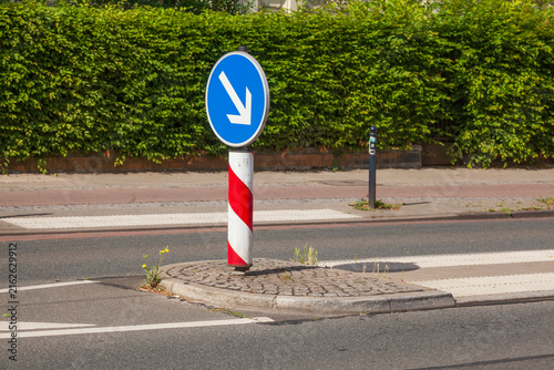 Verkehrsinsel auf Straße mit Pfeilwegweiser und  Fußgängerübergang, Deutschland