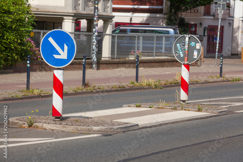 Verkehrsinsel auf Straße mit Pfeilwegweiser und  Fußgängerübergang, Deutschland