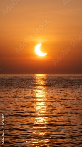 Partial Solar Eclipse Over Ocean Horizon. Crescent Sun in Golden Sunset Sky. Astronomical Phenomenon Reflection on Water Surface. Natural Space Event Skyline.