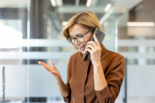 Fotografía Woman in glasses talking on her smartphone, expressing anger and stress during a