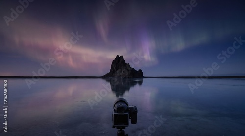 Professional photographer capturing the northern lights over a frozen landscape