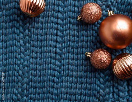 Top view of braided blue wool sweater background with copper christmas ornaments and copy space