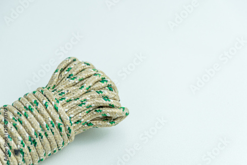 Rolled bundle of green and white twisted string rope isolated on white background