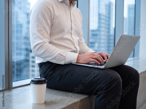 Professional businessman working on a laptop near a modern office window