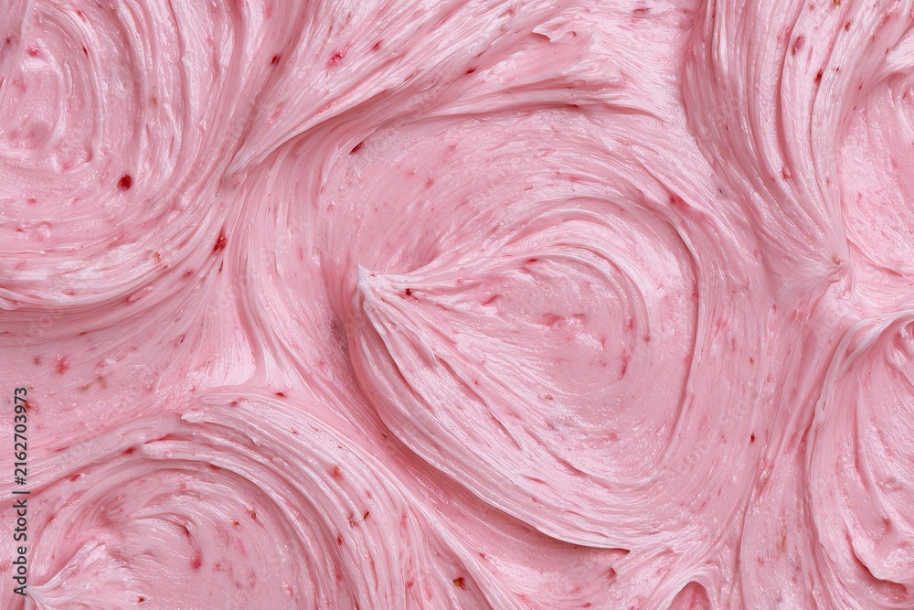 Obraz premium Creamy pink frosting spreads on a cake with swirl patterns