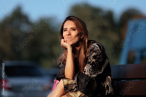 Quadro su tela Thoughtful Woman Sitting On Bench Resting Chin On Her Hand