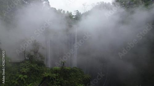 Majestic tumpak sewu waterfall revealing itself from the morning fog in east java, indonesia