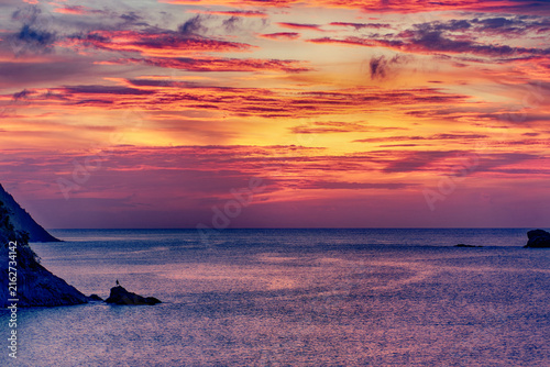Silhouette of person on a rock in the Caribbean sea at sunset