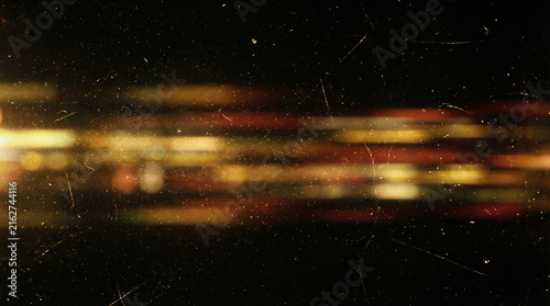 Abstract dark cinematic background with horizontal motion blur light streaks in gold, yellow, and orange tones, featuring a vintage grunge analogue film texture with fine dust and scratches.