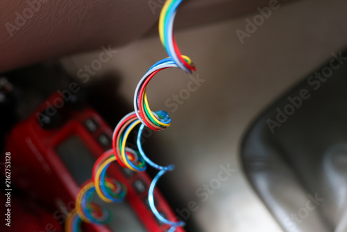 Obraz na plátně Colorful electrical wire curl with exposed copper ends over blurred red tool and