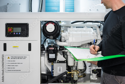 Fotografie Caucasian Male Superyacht Engineer working on the engine room, inspecting the ge